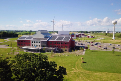 Red school with solar panels in front of a wind turbine.